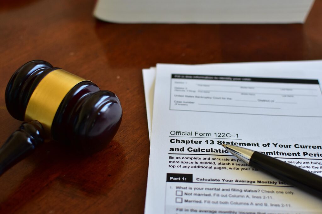 Chapter 13 Bankruptcy Repayment Plan with Calculator and Gave A professional concept shot of Official Form and Form 122C-1 for Chapter 13 wage earner's bankruptcy plan. Featuring a calculator, house keys, and a judge's gavel to symbolize debt reorganization, mortgage protection, and structured monthly repayment.